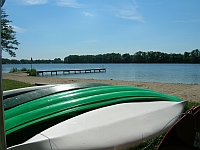 Zu sehen sind Bootsrücken vor einem See bei Sonnenschein