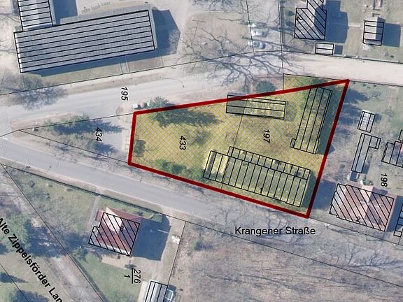 Luftbildkarte: Ein unregelmäßig dreieckiges Grundstück an der Krangener Straße ist rot markiert; darin mehrere längliche Gebäudeflächen. Umgebende Bebauung und Grundstücksnummern deuten die Lage im Quartier an.