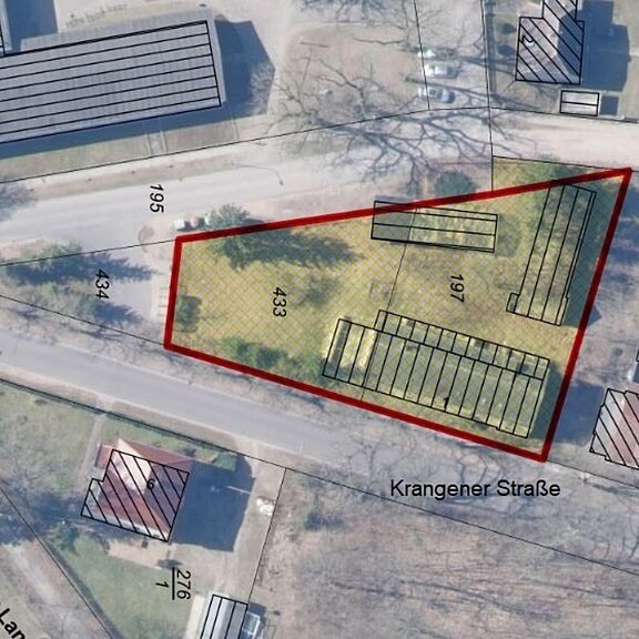 Luftbildkarte mit rot umrandetem, dreieckigen Grundstück an der Krangener Straße. Innerhalb liegen mehrere schraffierte Gebäudegrundrisse und Flurstücksnummern. Umgebende Straßen und Nachbargebäude sind blasser dargestellt; Fokus liegt auf dem markierten Areal.