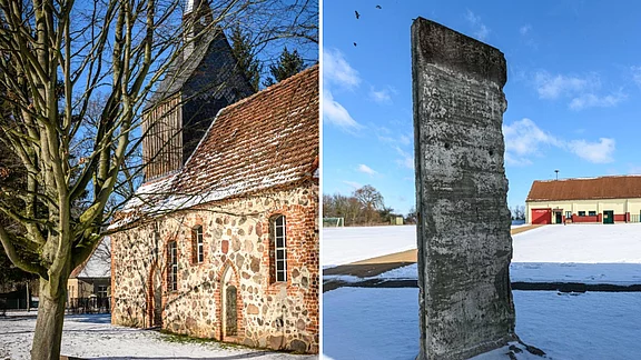Eine historische Kirche mit steiniger Fassade und schneebedecktem Gelände steht links. Rechts ist ein grauer Betonsockel, möglicherweise ein Teil einer Mauer, der vor einem Sportplatz und einem Gebäude steht, alles umgeben von Schnee und klarem Himmel.