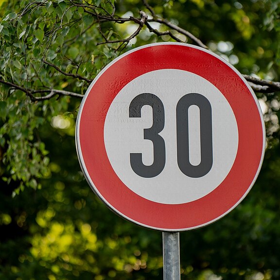 Rundes Verkehrsschild mit rotem Rand und schwarzer Zahl 30 auf weißem Grund, zeigt eine zulässige Höchstgeschwindigkeit von 30 km/h an.