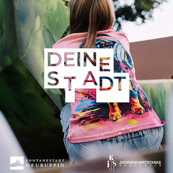 Rückansicht eines Kindes, das eine Wand gestaltet; rosa Hoodie mit buntem Hundemotiv. Darüber prangt der Schriftzug DEINE STADT. Stimmung: kreative Mitgestaltung des urbanen Raums.